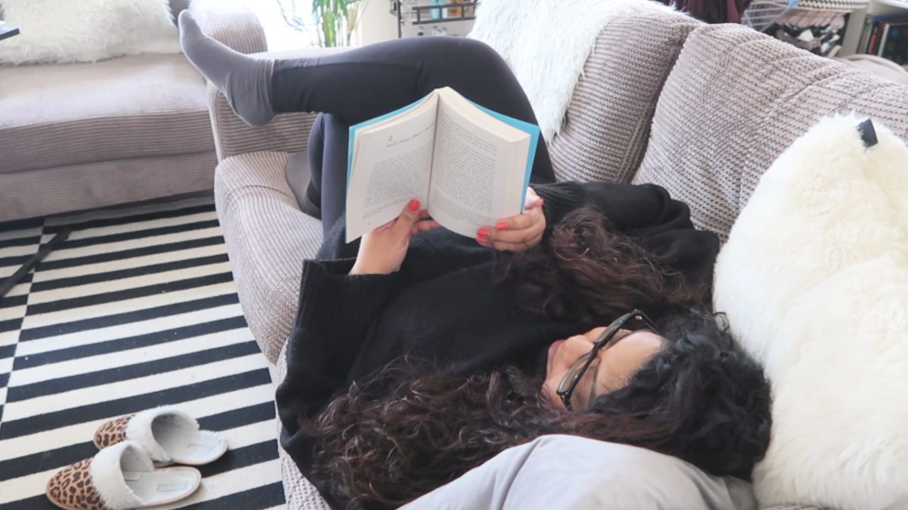 101 things to do in isolation, image of a woman lying on the sofa reading a book, nishi v