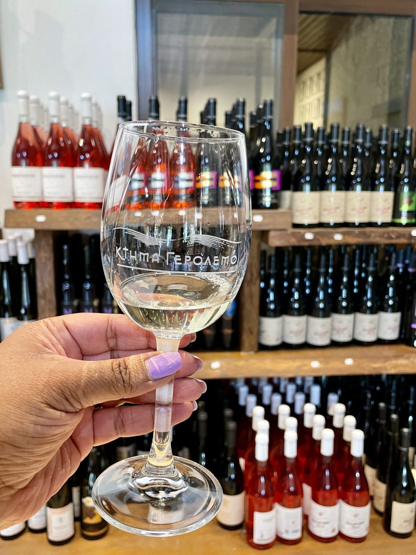 my hand holding a glass of white wine in a winery Ktima Gerolemo