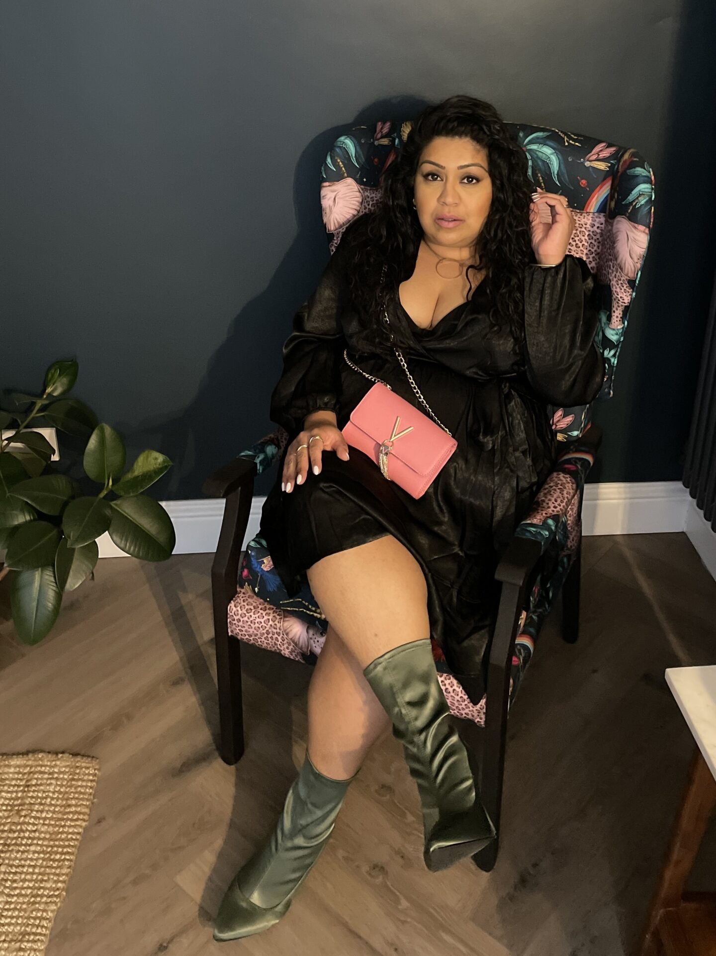me sitting in a dark room wearing a black dress, green sock boots and a pink crossbody bag