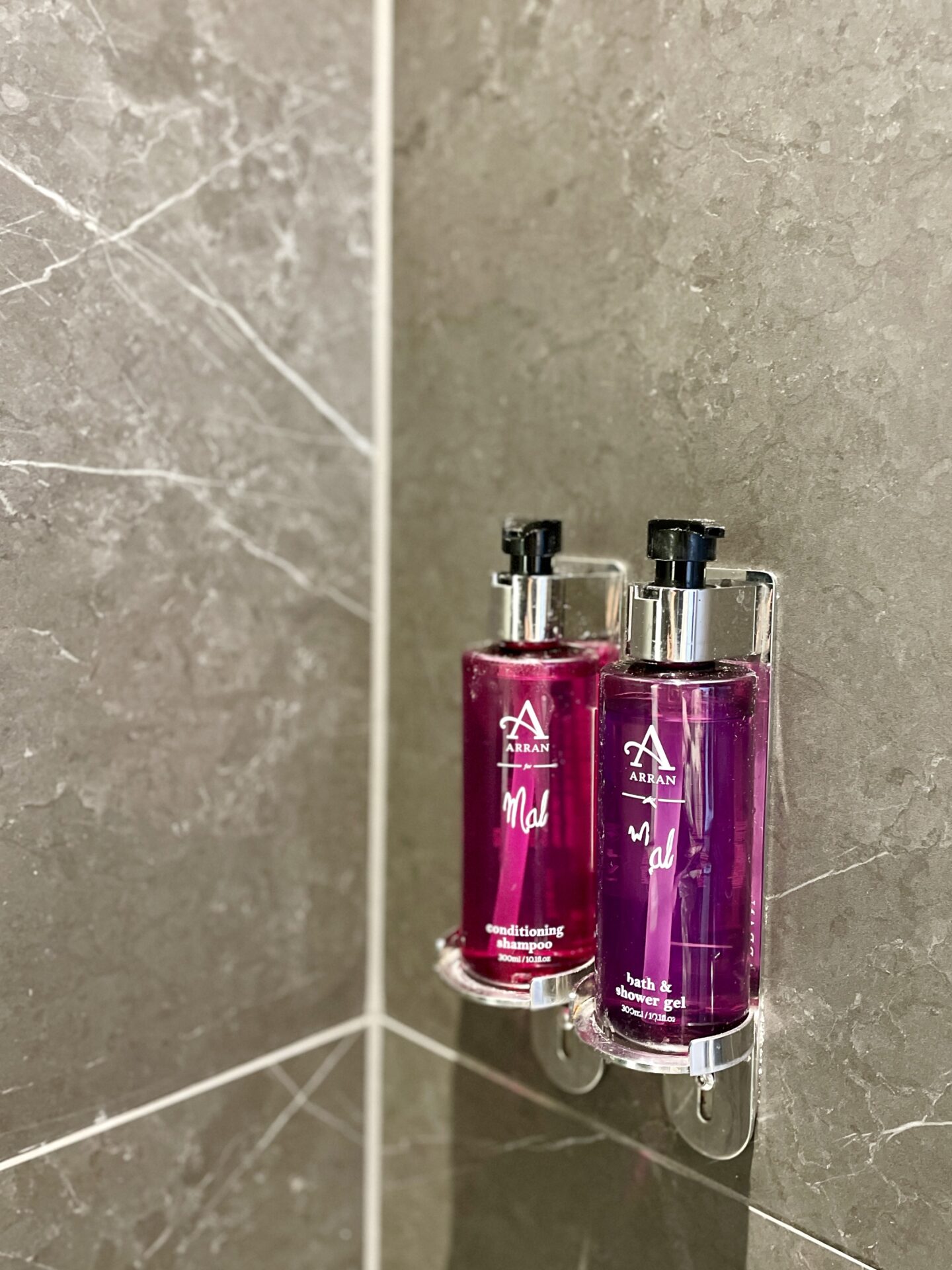 Body wash and shower gel against grey concrete effect tiles inside a shower
