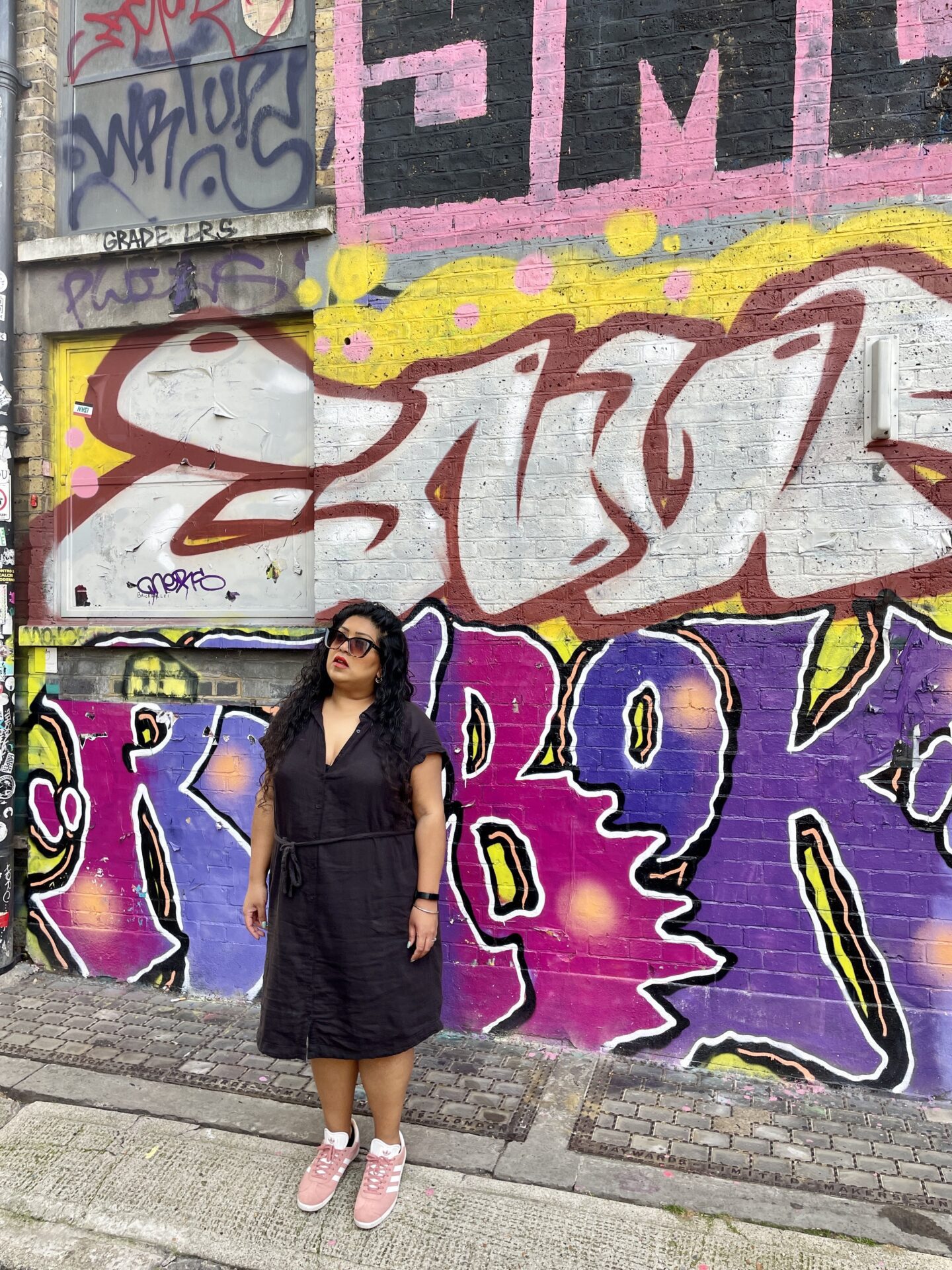 woman posing in front of shoreditch street art