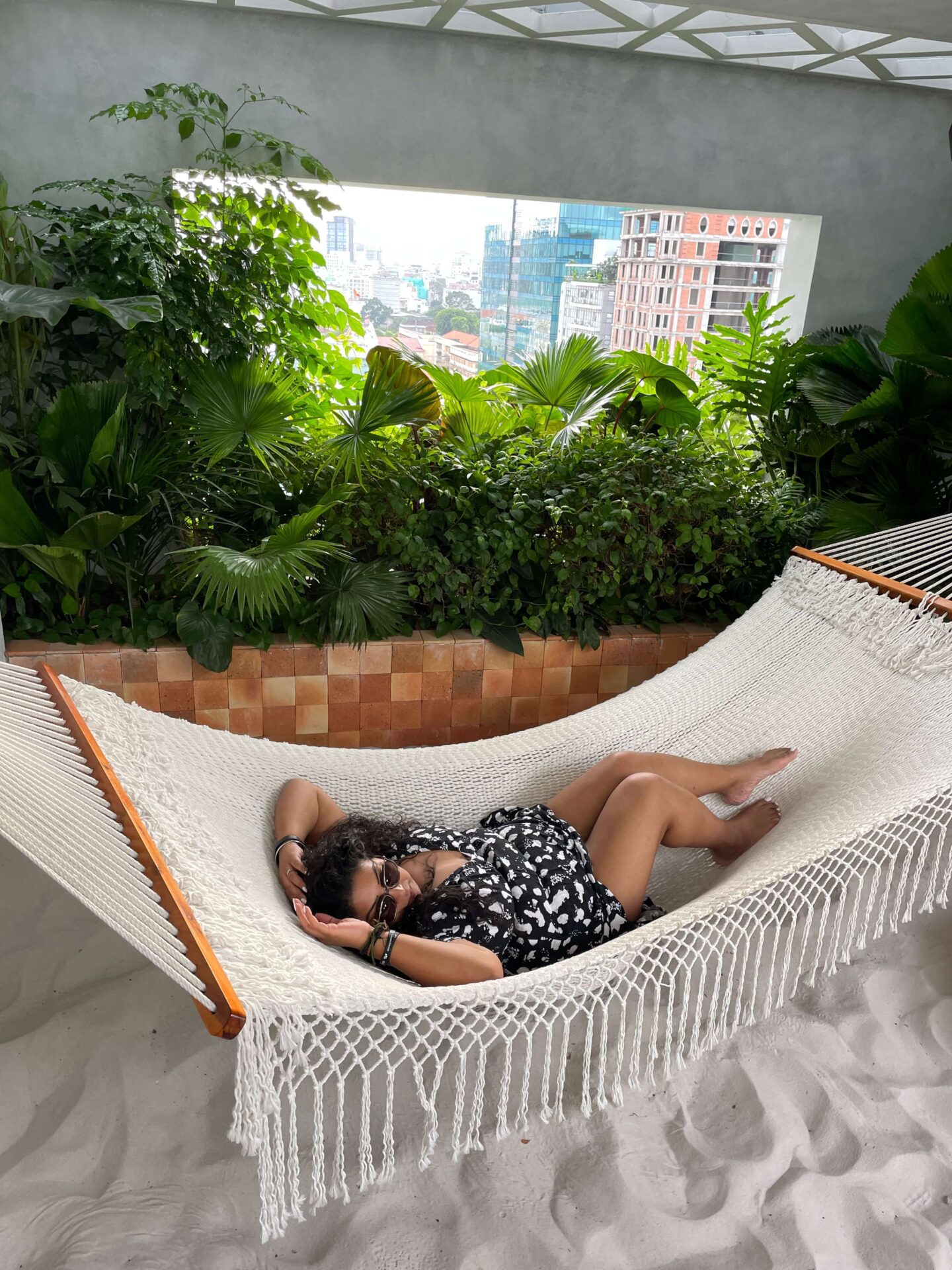 woman in a hammock by a rooftop pool in HCMC