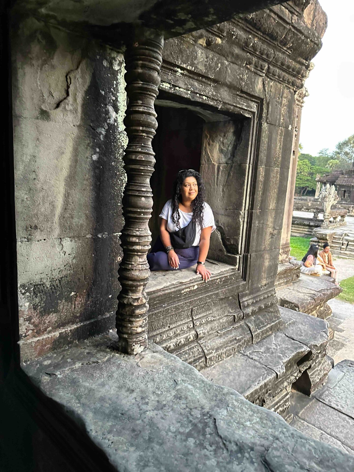girl sat looking at angkor wat temple complex