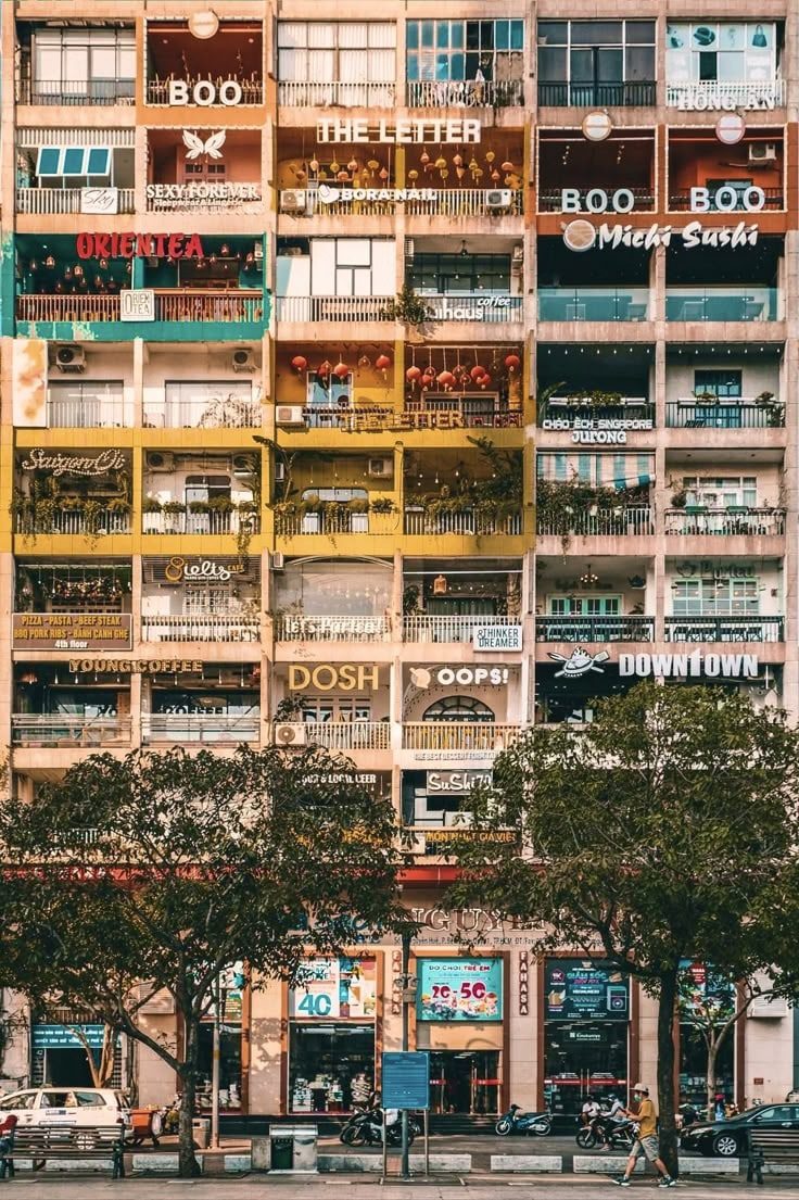 The Cafe Apartment building in Ho Chi Minh city. It shows 9 floors of vibrant signs for shops, boutiques and cafes on a tiny pedestrian street