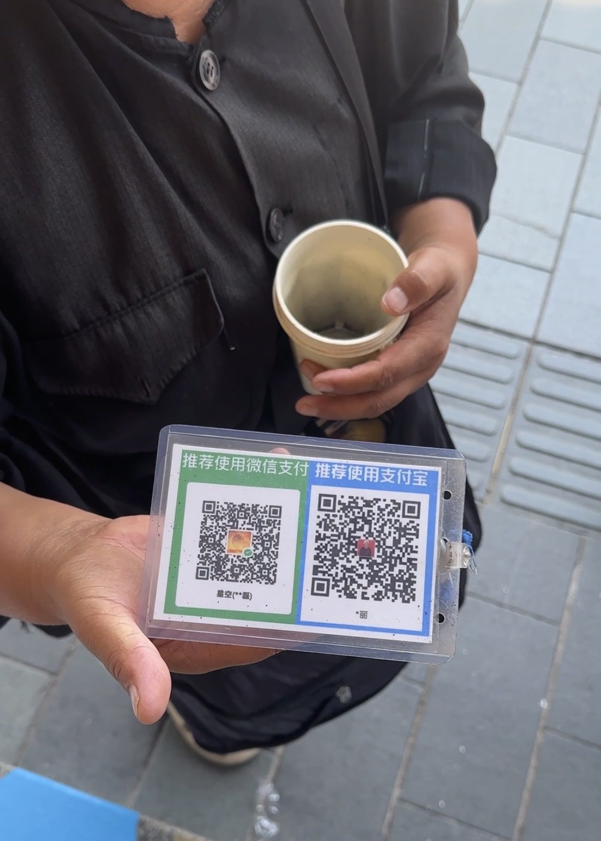 A beggar in Shanghai holding out QR codes for Alipay and Wechat for payment
