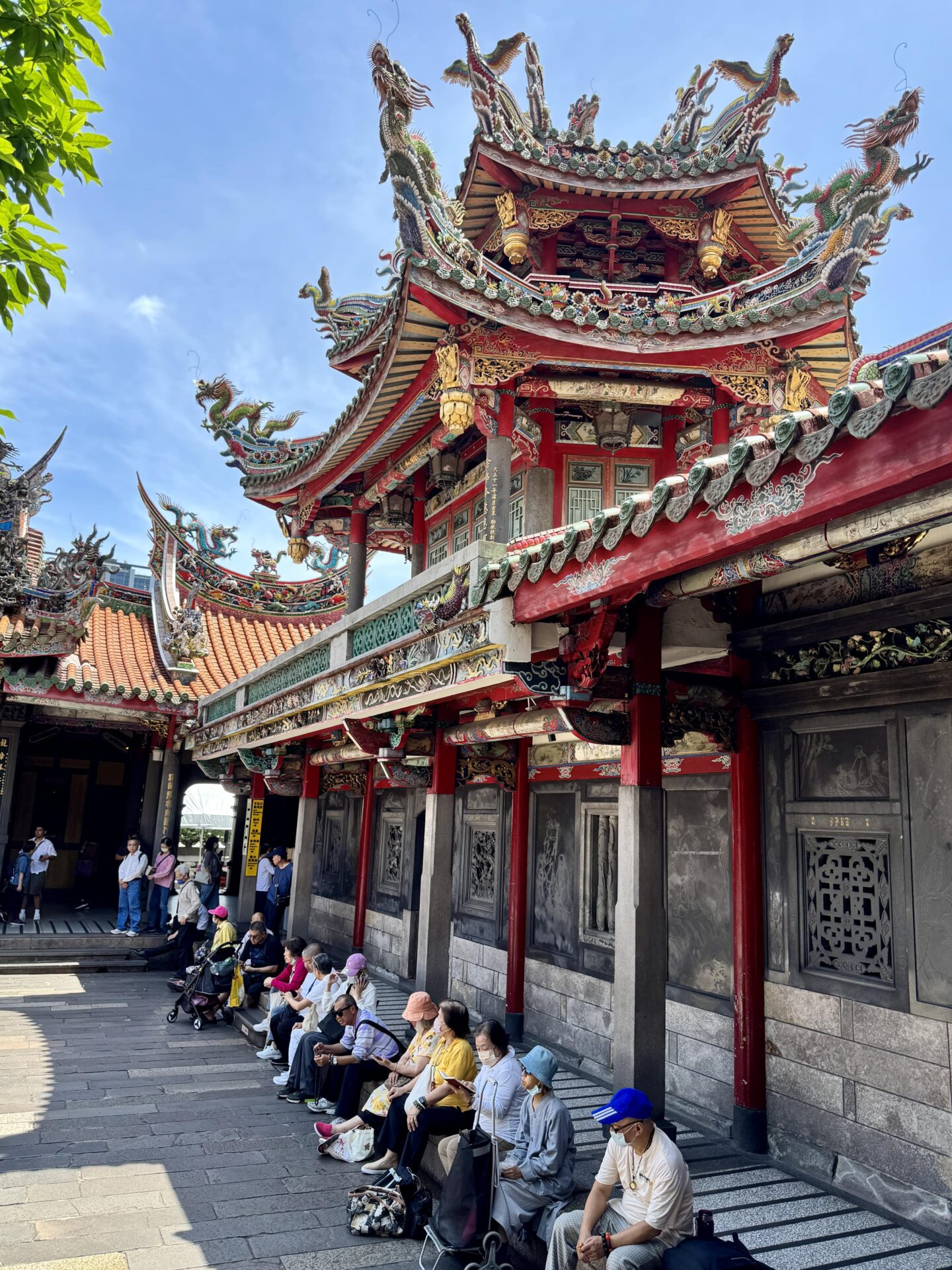 people sitting in the courtyard at Longshan Temple in Taipei