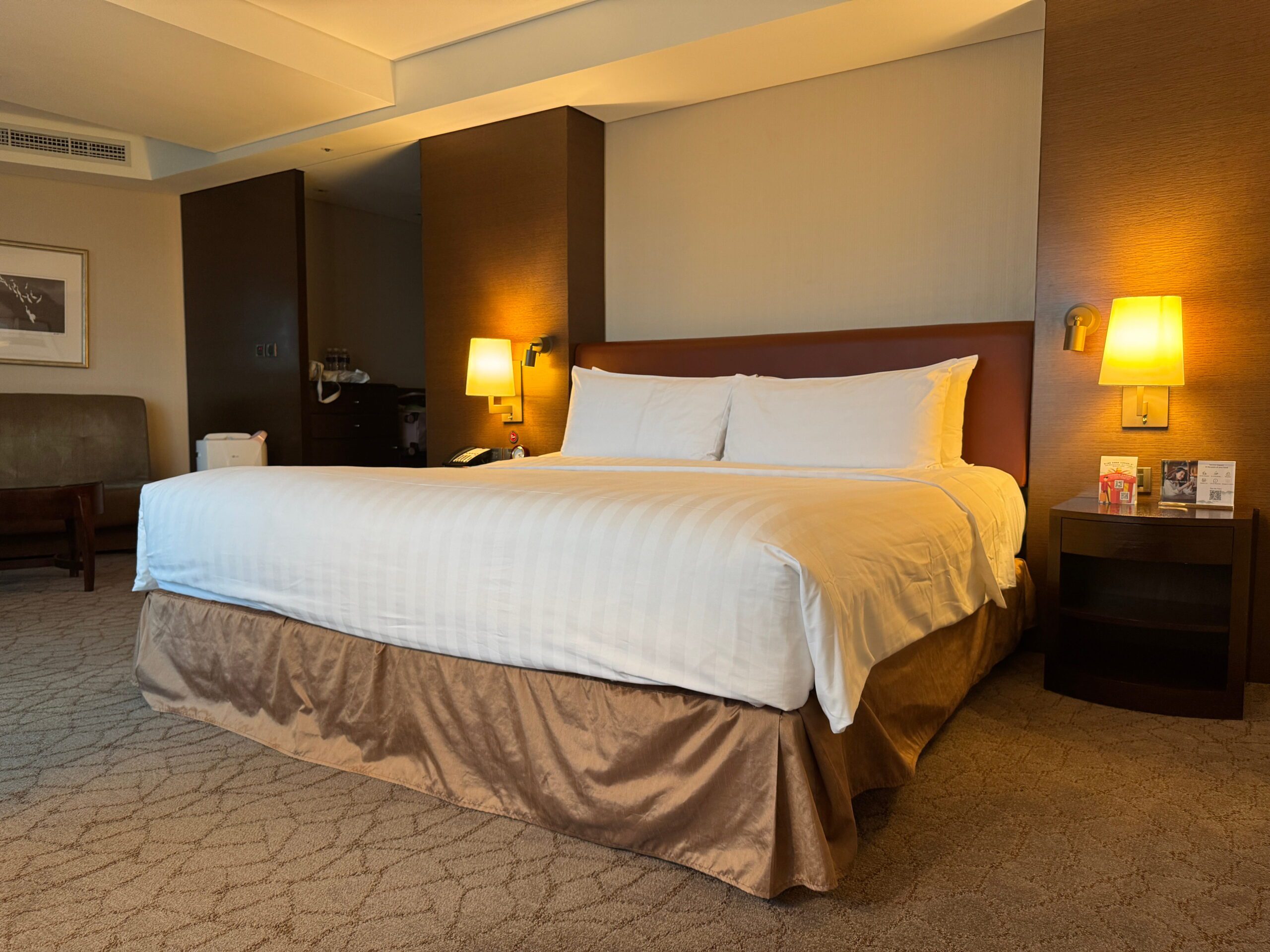 King bed in a Shangri La Far Eastern Tainan hotel room with warm bedside lighting neutral tones and a cozy seating area.